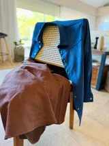 Sobrecamisa de gamuza con cuello clásico, cierre frontal con botones metálicos y mangas largas con puños abotonados. Presenta un diseño estructurado con corte recto y largo a la cadera.