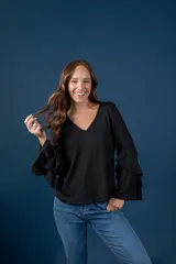 Blusa gris melange de punto tejido fino, con escote en V y mangas largas anchas terminadas en volados.