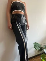 Pantalón de cuero negro con textura de piel de cocodrilo y rayas blancas laterales.