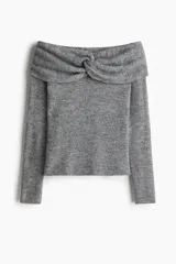 Buzo de punto acanalado con escote off-the-shoulder y detalle de nudo frontal. Presenta mangas largas y diseño ajustado.