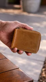 Billetera de cuero color marrón claro con cierre perimetral. En el interior, cuenta con compartimentos para billetes, tarjeteros y un monedero con broche.