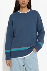 Sweater de punto color azul con cuello redondo, mangas largas y puños acanalados. Presenta una franja horizontal en contraste de color turquesa y bordó en el ruedo y en los puños.