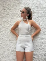 Mono corto de lurex color plateado, con escote halter y lazo al cuello.