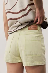 Short gris claro de tiro alto con costuras pespunteadas en contraste y bolsillos traseros amplios. Presenta una etiqueta de cuero rojo en la parte posterior de la cintura.