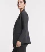 Blazer alargado color gris oscuro, con cuello solapa, bolsillos incorporados y cierre frontal con dos botones.