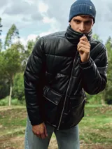 Campera puffer negra de cuero sintético con cierre frontal y cuello alto.