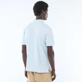 Remera polo de piqué color celeste, con cuello y bordes de mangas en tono contrastante, cierre frontal con botones y pequeño logo bordado en el pecho.