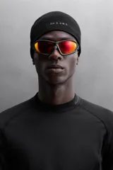 Camiseta negra de running de primera capa, confeccionada en tejido elástico y ajustado al cuerpo. Tiene cuello alto con logo estampado, mangas largas con puños ajustables y costuras planas.