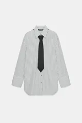 Camisa oversize de popelín a rayas verticales blancas y negras, con cuello solapa, hombros caídos y puños anchos. Incluye una corbata negra lisa.