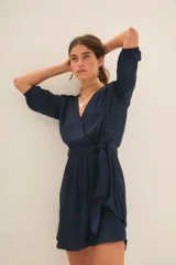 Vestido corto azul marino de manga larga con efecto abullonado en puños, escote cruzado en V y lazo ajustable en la cintura.