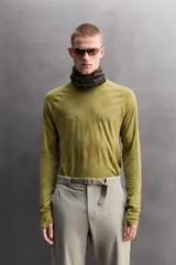 Camiseta térmica de manga larga ranglán, cuello redondo, color verde oliva con efecto tie-dye o jaspeado. Presenta tejido con lana, alta elasticidad y ajuste al cuerpo, con estructuras combinadas para facilitar la transpiración y sin costuras.