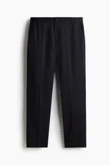 Pantalón tobillero de sarga de algodón con pliegues frontales, cintura elástica, cierre con botón, bolsillos laterales al bies y bolsillos traseros ribeteados con botón. Presenta un corte ajustado slim fit.