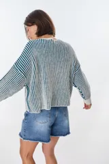 Sweater de punto a rayas verticales blancas y negras, con cuello redondo y mangas largas.