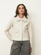 Chaqueta corta de paño color azul oscuro, con cuello camisero, cierre frontal con botones metálicos dorados y bolsillos frontales con solapa.