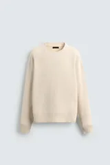 Jersey de corte relajado confeccionado en tejido de algodón con textura. Presenta cuello redondo, manga larga y acabados en rib en cuello, puños y bajo.