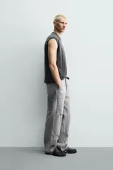 Pantalón de jean estilo carpintero con corte relaxed fit, tiro medio y pierna recta. Presenta un lavado azul medio con efecto desgastado y roturas en las rodillas. Incluye bolsillos laterales tipo plastrón, tira multifunción en la pierna, cierre frontal con cremallera y botón.