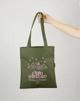 Tote bag color verde oliva con estampado frontal en color rosado que incluye un perro, hojas cayendo y la leyenda Otoño Uruguayo.