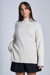 Sweater color crema de media polera, corte holgado y mangas largas. Tejido de punto con detalles acanalados en cuello, puños y ruedo.