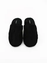 Pantuflas de estar por casa color negro, confeccionadas en tejido de pana con textura acanalada y suela plana.