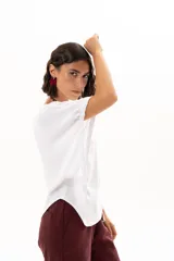 Blusa blanca de corte holgado y diseño minimalista, con mangas cortas tipo murciélago que presentan un detalle de fruncido lateral con cordón ajustable.
