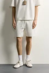 Bermuda estilo jogger de ajuste relajado, confeccionada en tejido interlock de algodón. Cuenta con cintura elástica ajustable con cordón, bolsillos frontales de vivo y diseño liso.