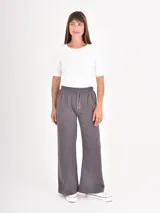 Pantalon de estilo deportivo en color gris oscuro, confeccionado en tejido de punto suave. Presenta un corte recto y holgado, cintura elástica con cordón ajustable y costuras verticales decorativas en el frente.