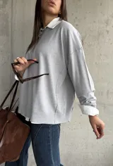 Sweater de punto color gris, de corte holgado y diseño de manga larga con costuras visibles en los hombros. Presenta cuello redondo y puños acanalados.