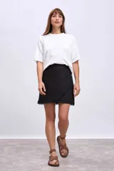 Minifalda negra cruzada con detalle de flecos en el borde.