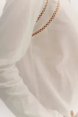 Remera blanca de manga larga con escote a la base. La parte delantera es de algodón y la espalda de remería para mayor elasticidad. Las mangas combinan ambas telas y presenta un detalle de doble entredos en la sisa delantera.