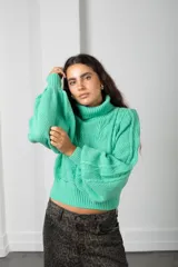 Polera de tejido de punto color verde menta, con cuello alto, mangas largas abullonadas y puños y cintura acanalados.