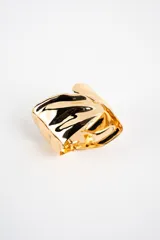 Brazalete rígido de metal dorado con diseño de superficie ondulada y brillante.