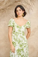 Vestido midi blanco con estampado floral en tonos verdes, escote en V, mangas cortas abullonadas y corte evasé con abertura lateral.