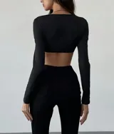 Top negro de mangas largas con escote cuadrado y abertura en el pecho con detalle metálico dorado.