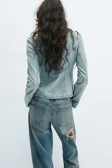 Camisa de denim celeste con cuello solapa, manga larga y cierre frontal con nudos de tela.