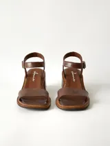 Sandalias de cuero color chocolate, con taco cuadrado de 6 cm, tira ancha en la parte delantera y tira en el tobillo con hebilla metálica ajustable.