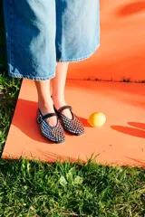 Ballerinas tipo Mary Jane de cuero nobuck negro, completamente cubiertas de apliques metálicos plateados. Tienen tira con hebilla en el empeine y diseño de punta cuadrada.