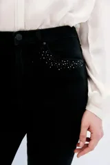 Jean slim negro de tiro medio-alto, con calce al cuerpo y pierna semi-recta. Presenta detalles de hotfix en los bolsillos delanteros y en los puños.