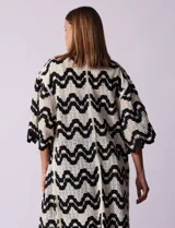 Cardigan largo de crochet color crudo con diseño de ondas en negro.