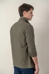 Sobre camisa color verde militar de lino con cuello clásico, manga larga con puños abotonados, cierre frontal con botones a tono y bolsillos de parche en el pecho.