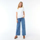 Pantalón de embarazo de corte ancho y tiro alto, confeccionado en denim azul con bordados de pequeñas flores blancas. Presenta un diseño cómodo con cintura elástica adaptada para el periodo de gestación.