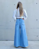 Pantalón de jean color beige, de corte recto y tiro alto, con ruedo deshilachado y cierre frontal con botón y cremallera.