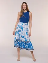 Vestido midi combinado de la marca Figueroa & Flower, con torso de modal azul sin mangas y cuello redondo, y falda evasé de rayón con estampado floral y paisajes en tonos blancos y azules, con cintura elastizada y lazo para anudar.