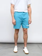 Bermuda deportiva celeste de piqué con cordón ajustable en la cintura, bolsillos laterales y logo Umbro estampado en blanco en la pierna izquierda.