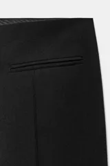 Pantalón capri negro de tiro medio, con bolsillos falsos de vivo en el delantero, raya planchada y aberturas laterales en el bajo.