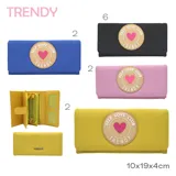 Billetera negra con cierre de solapa y broche a presión. Estampado frontal con parche redondo color beige con borde blanco y texto "SELF LOVE CLUB TRENDY" en negro y corazón rosa en el centro.