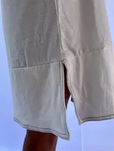 Vestido playero de corte holgado y diseño minimalista, confeccionado en algodón. Presenta cuello redondo, sisas amplias y aberturas laterales en el ruedo con pespuntes en contraste.
