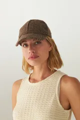 Gorra con visera confeccionada en lana fina sin teñir, con un sutil patrón de tejido en espiga.