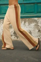 Pantalón tejido de corte amplio y tiro medio, con diseño de franjas laterales en tonos contrastantes marrón y beige. Posee cintura elástica y terminación de ruedo sin costura.