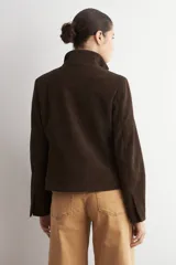 Chaqueta de cuero color marrón oscuro, con cuello alto, cierre frontal y diseño minimalista de corte recto.
