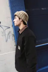 Sobrecamisa negra de corte clásico con cuello camisero en contraste color marrón a cuadros. Presenta cierre frontal con botones, dos bolsillos frontales tipo parche y una etiqueta decorativa con el logo de la marca en el pecho.